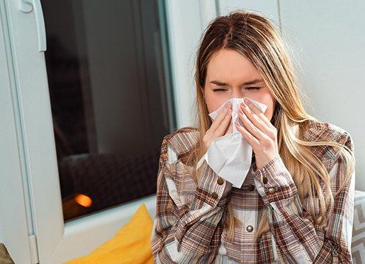 a women blowing her nose from allergies caused by pests