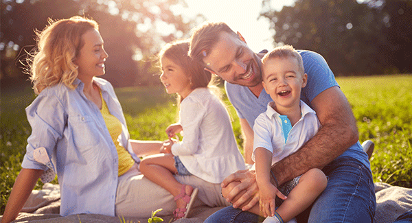 a mother and father with two small children laughing outside