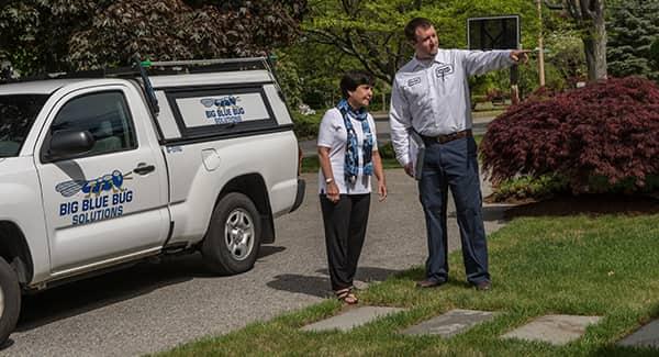 a view of a big blue bug solution technician walking a new england resident around their property while explaining the best pest control plan treatments available