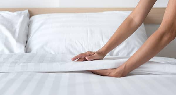 a portland maine house keeper checking for bed bugs as she is preparing for turnover during tourist season