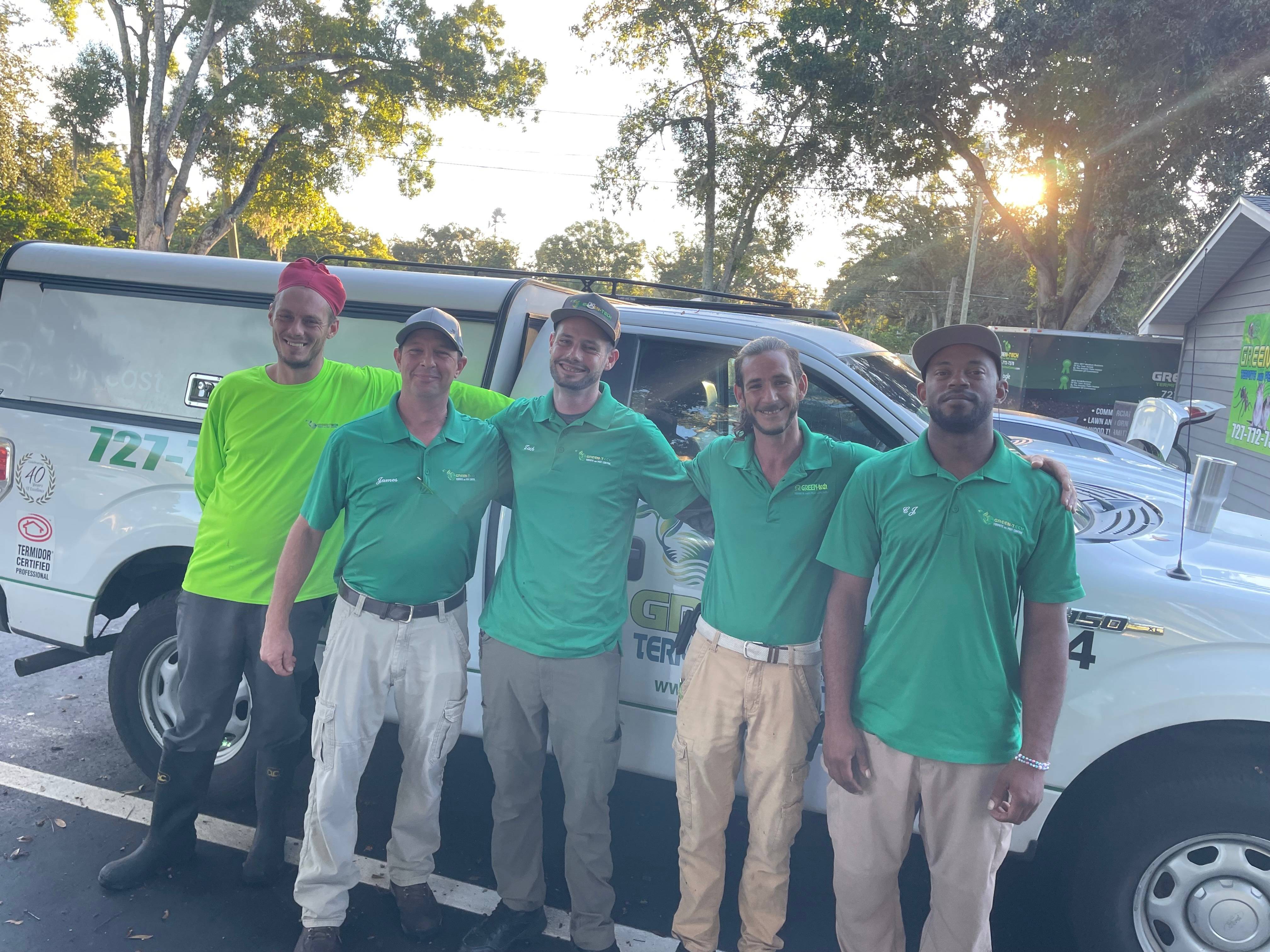 green tech team standing in front of a company vehicle