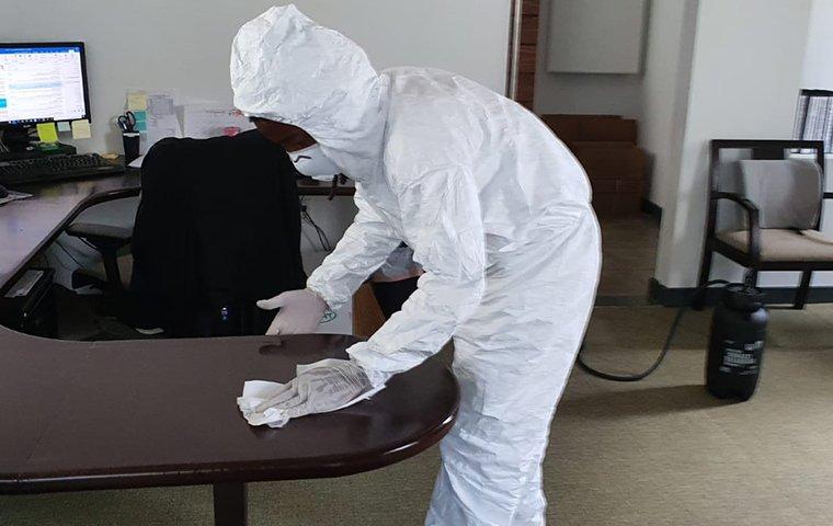 a tech wiping off a desk with a disinfecting wipe