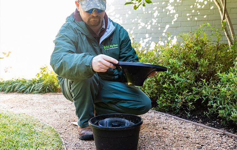 a technician kneeling over a mosquito trap in tarrant county
