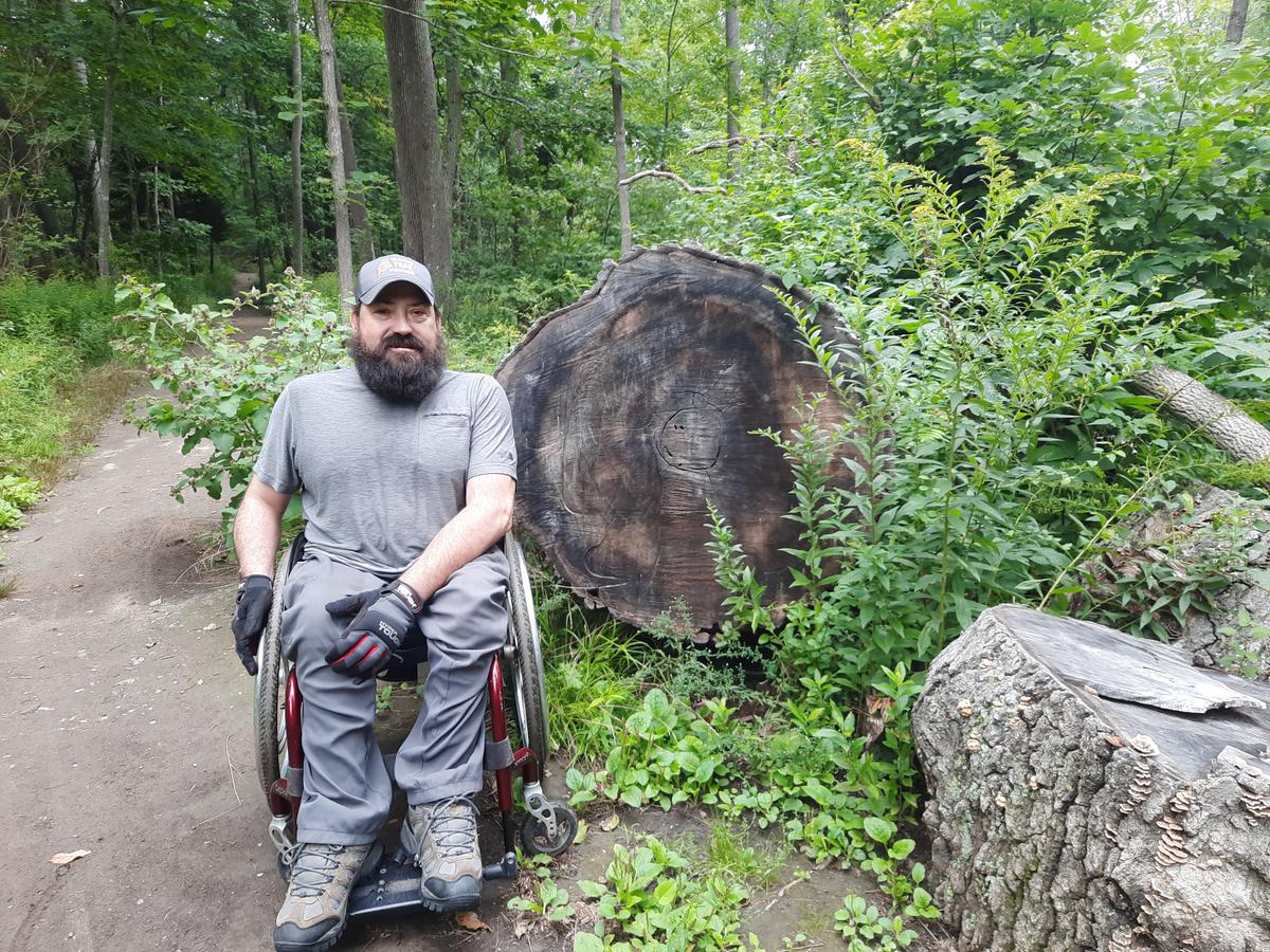 Enock next to a large downed tree. Photo credit: Enock Glidden