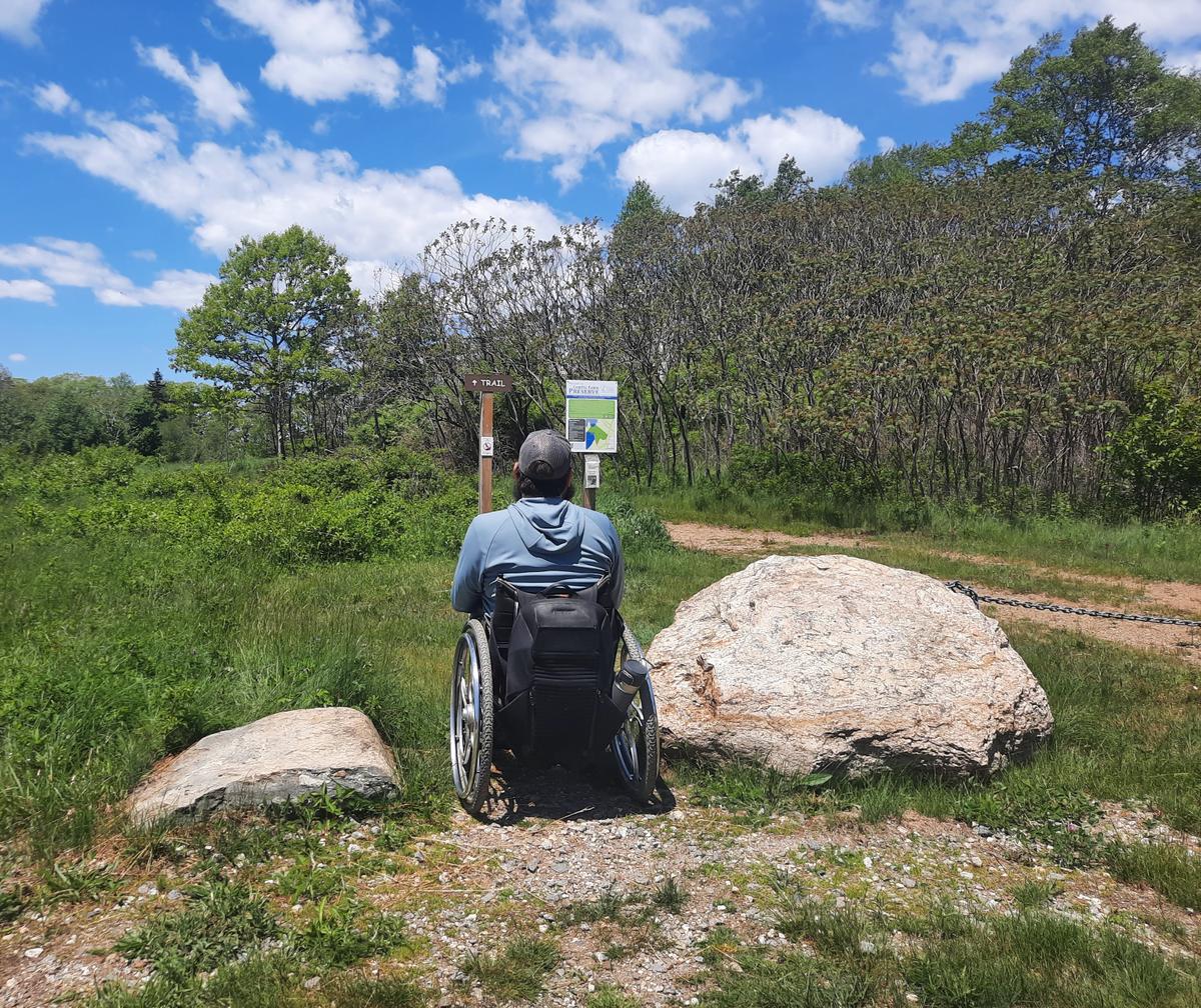 Enock demonstrating the width between boulders at the trailhead for the Curtis Farm Preserve.