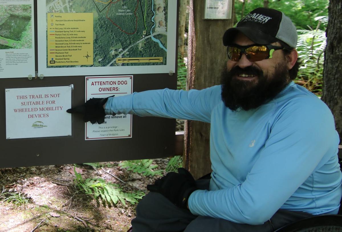 Enock pointing out the sign stating that the trail is not suitable for mobility devices.