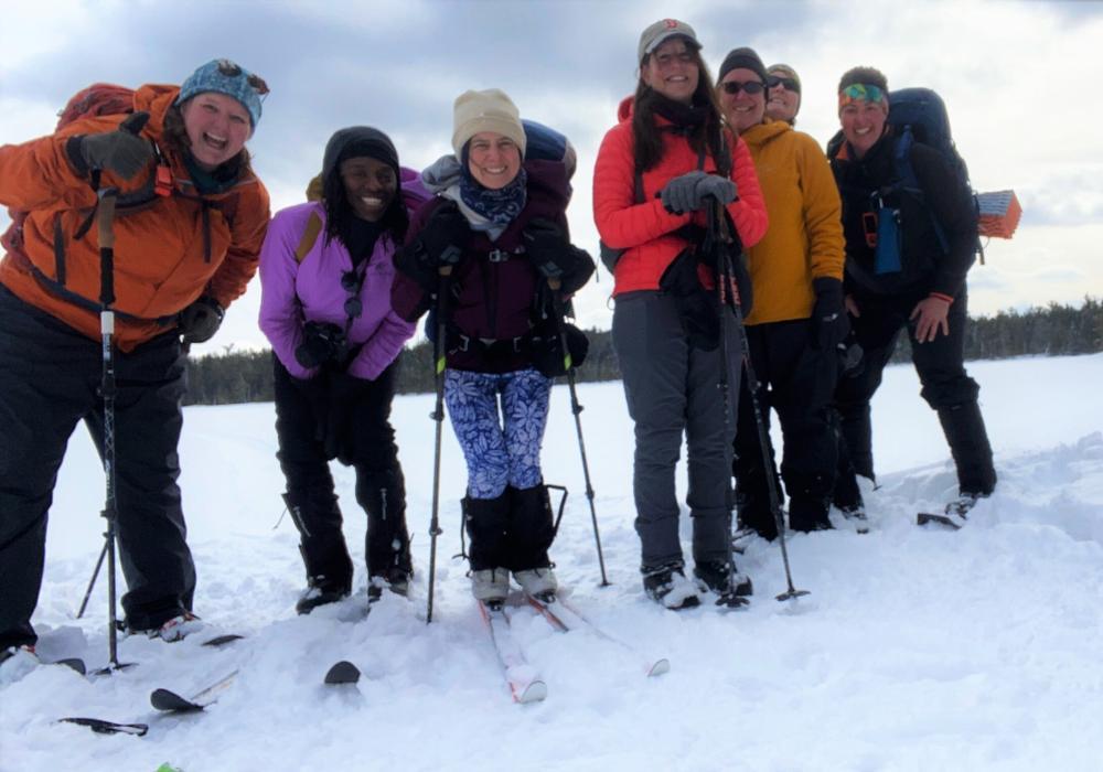 A group of women pause skiing & snowshoeing to smile at the camera
