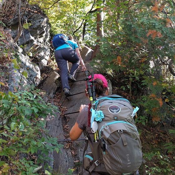 A hiker ascends a iron rung ladder