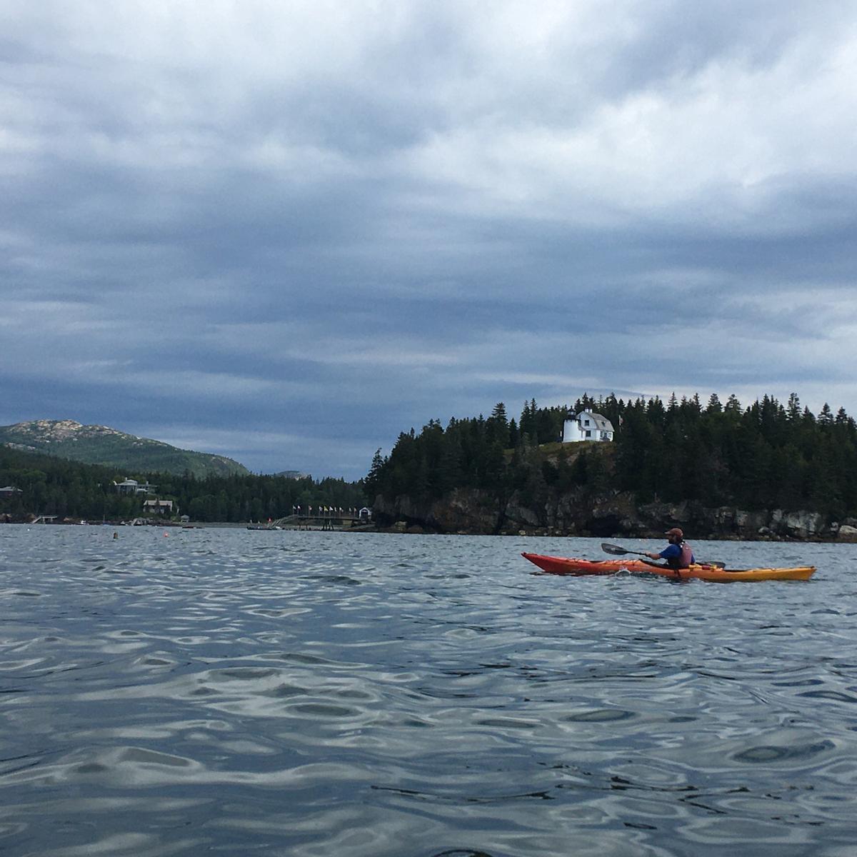 A sea kayaker paddles over small waves.