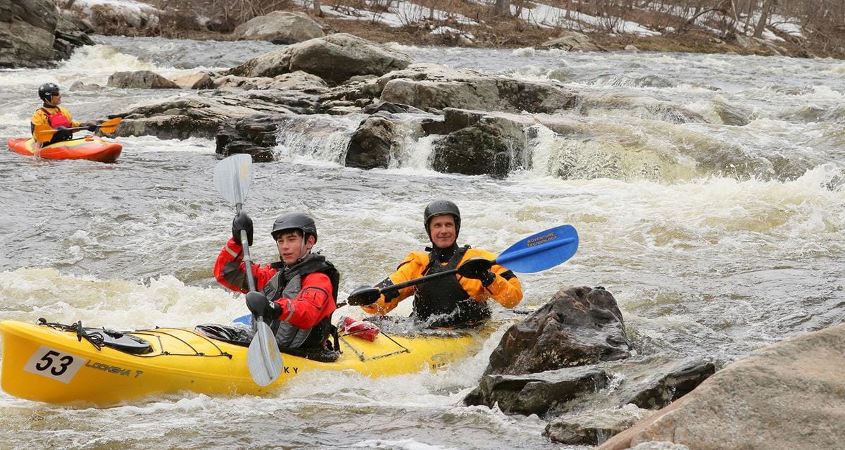 Kayakers paddle through a rapid