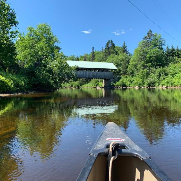 A calm river with a covered bridge in the background