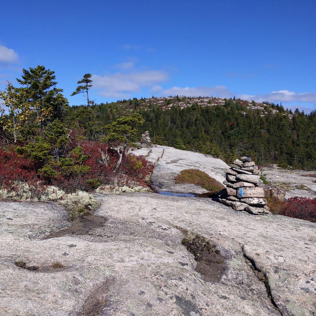 A rock cairn indicates the direction of the trail as it passes over a rock ledge