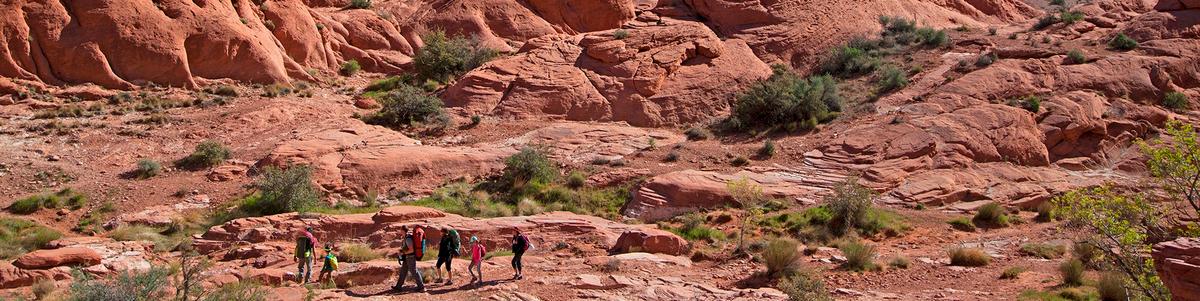 Hikers walk over red rocks