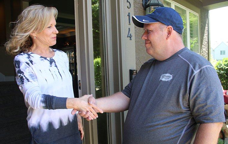 augustine exterminators technician shaking hands with a smiling customer in kansas city