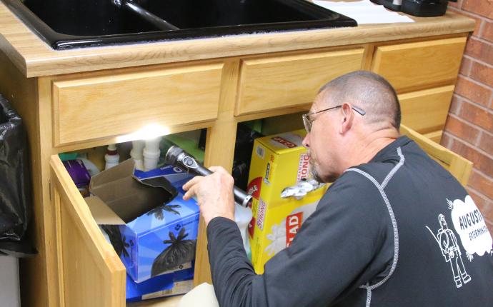 pest control technician checking under sink during free inspection