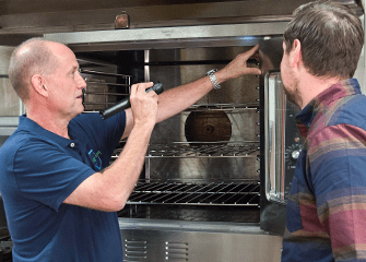 tech inspecting kitchen with business owner