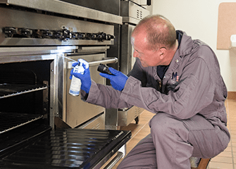 tech inspecting kitchen with business owner