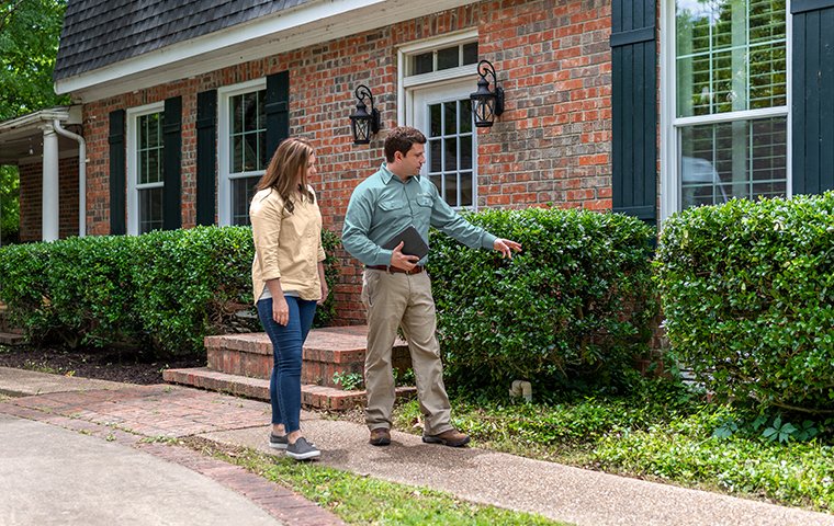 a pest technician inspecting with a homeowner
