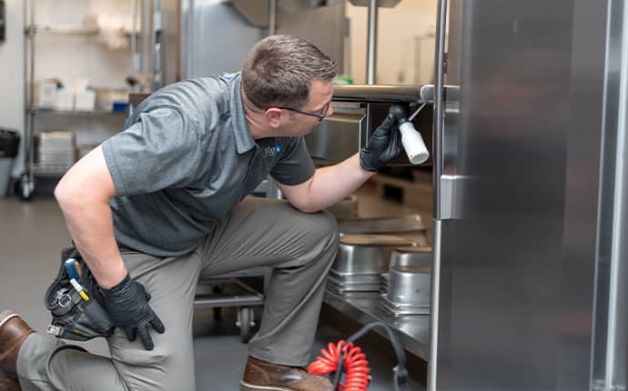prosite pest control service expert using integrated pest management services inside of a washington commercial kitchen
