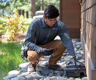 a prosite pest control service expert setting up a rodent station outside of a home in washington