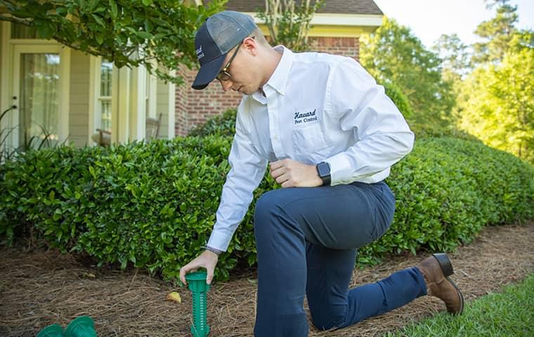 a technician inspecting a termite bait station in the yard of a home in new orleans