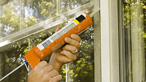 technician applying caulk to window