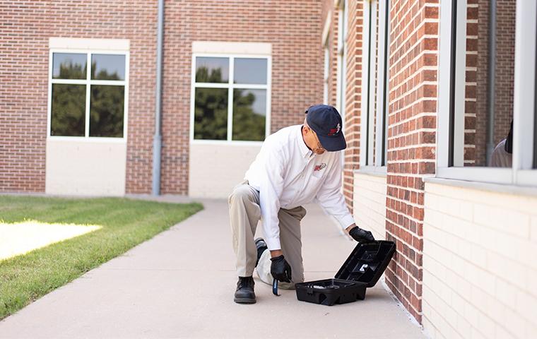 tech checking rodent station outside commercial building