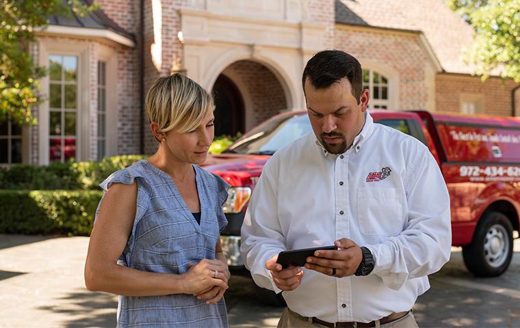homeowner and tech looking at a cellphone in the techs hand