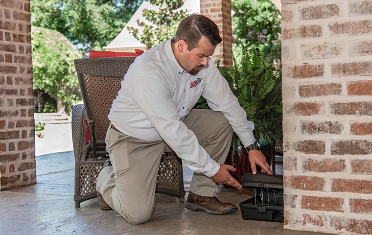 adams tech checking a rodent station outside a home in plano texas