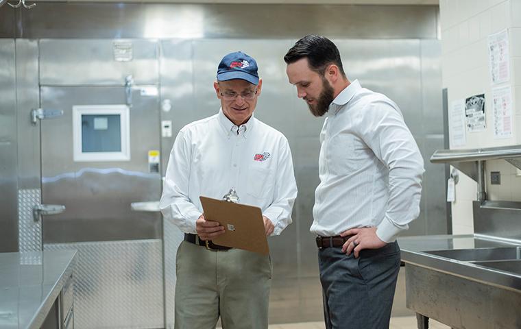 pest control technician discussing service plans with business owner