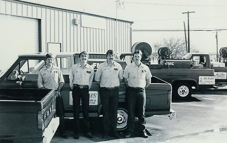 old picture of adams team in front of truck