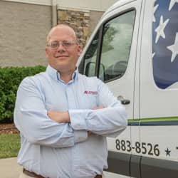 all-american pest technician in front of a service van