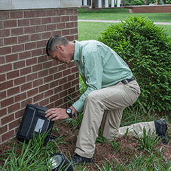 tech setting a rodent station outside a home