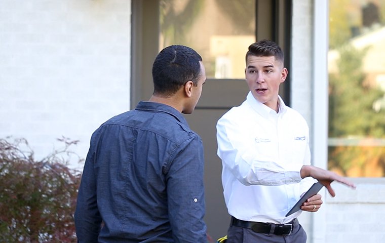 a pest control service technician reviewing pest control services with a homeowner