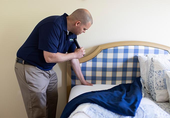 parkway pest services technician inspecting a bed for bed bugs