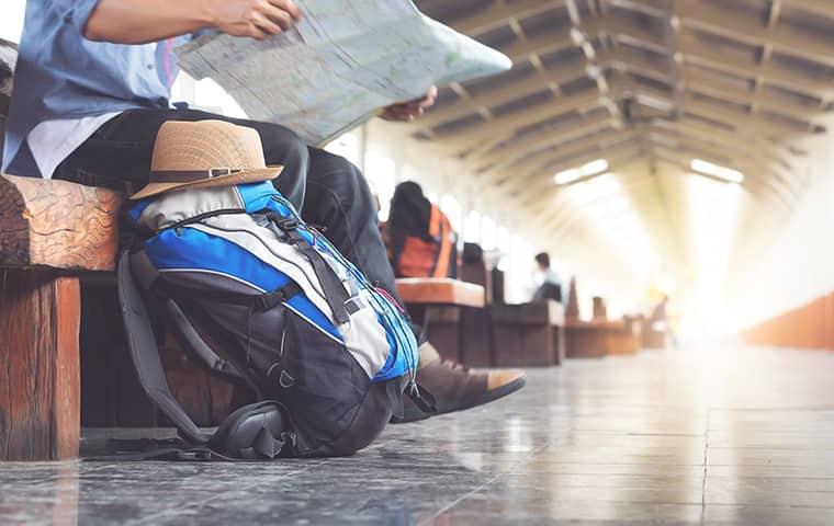 Don't Bring Bed Bugs Home With You When You Travel man traveling sitting in airport