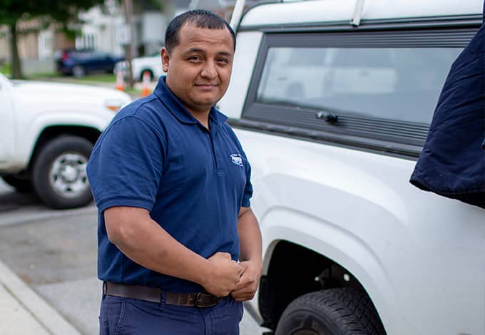 a parkway pest serviced technician posing in front of a company vehicle parked outside of a home in bedford village new york