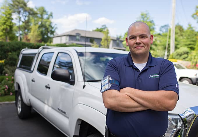 a parkway pest services technician posing in front of a company vehicle in muttontown new york