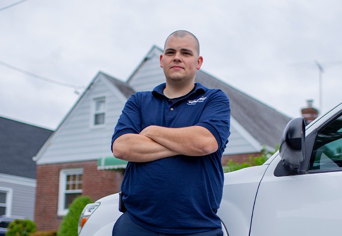 pest control technician standing by vehicle outside home in malverne new york