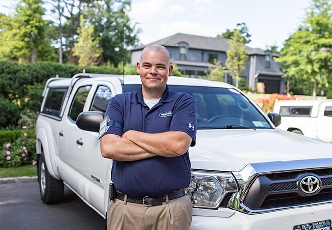 a parkway pest services technician posing in front of a company vehicle in mineola new york