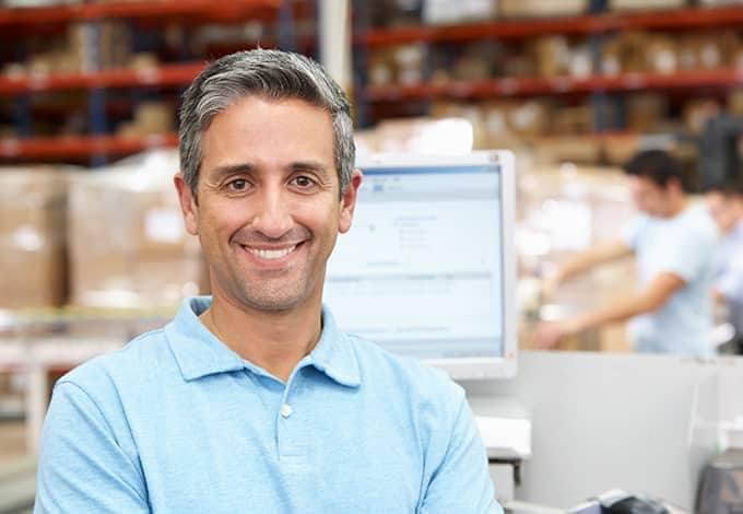 a smiling business owner in his warehouse in new york