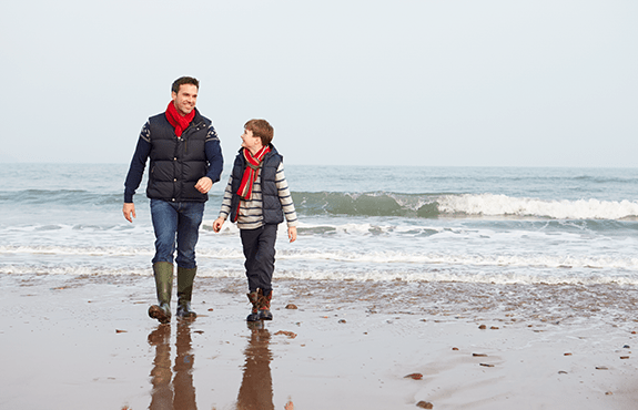 father and son walking on beach