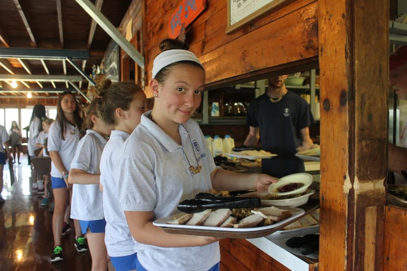 A girl helps serve lunch at Camp Tapawingo, Maine.
