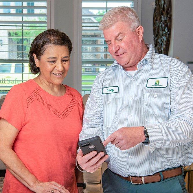 pest control technician and customer looking at a phone