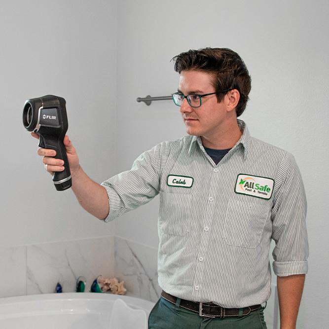 pest control technician with an infrared camera in a bathroom