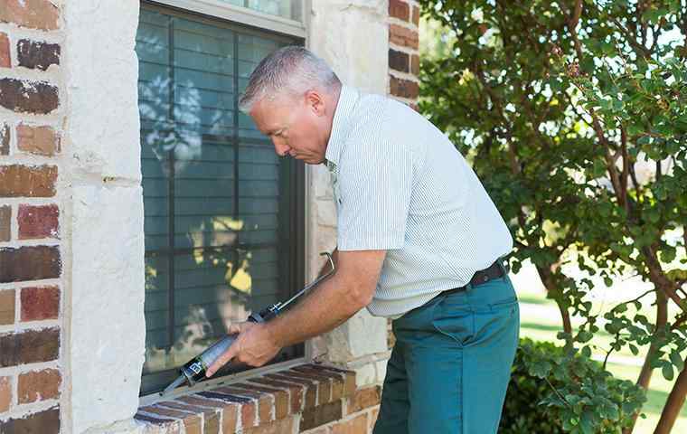 a pest control tech treating the exterior of a home
