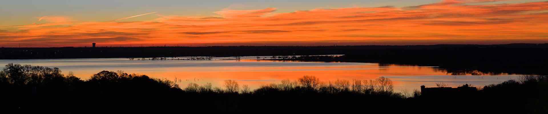 a view of a sunset over a pond in benbrook texas
