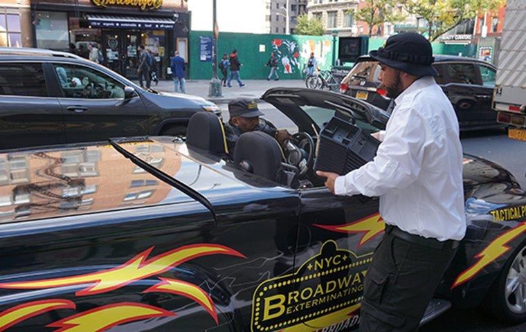 a broadway pest services tech standing next to vehicle in new york city