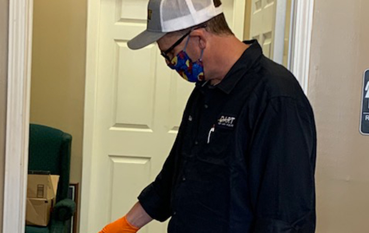 dart pest technician performing a pest control treatment wearing a mask