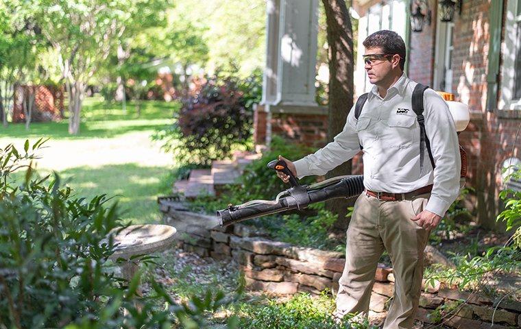 a pest technician performing an exterior mosquito treatment outside of a home in memphis tennessee
